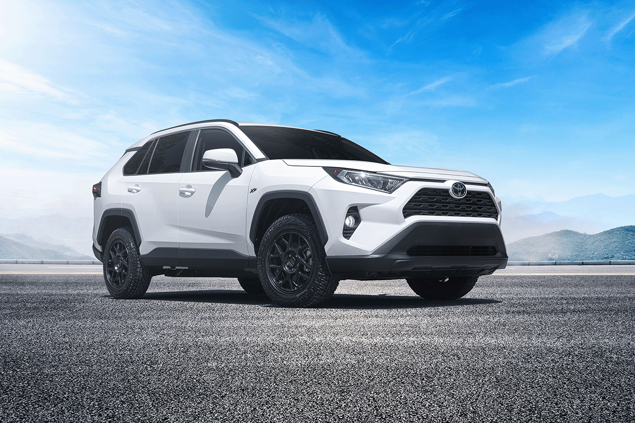 front side view of a white Toyota RAV4 XP XSeries upgraded accessories package with mountains and lots of blue sky in the background