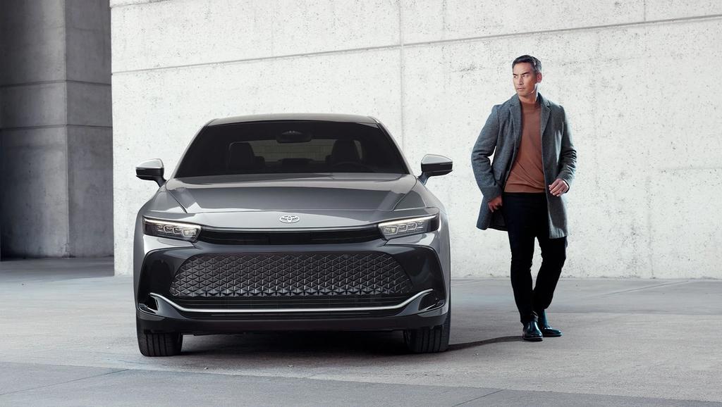 man standing beside a grey 2025 Toyota Crown with a concrete building behind them