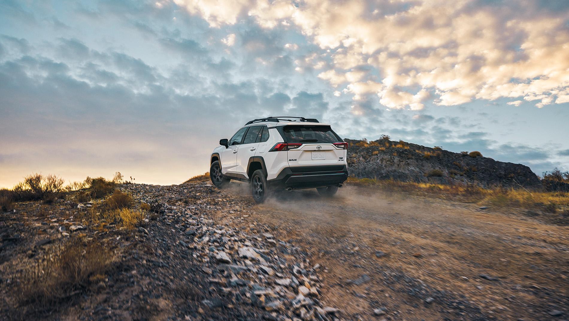 white Toyota RAV4 on a mountain road with colorful sky