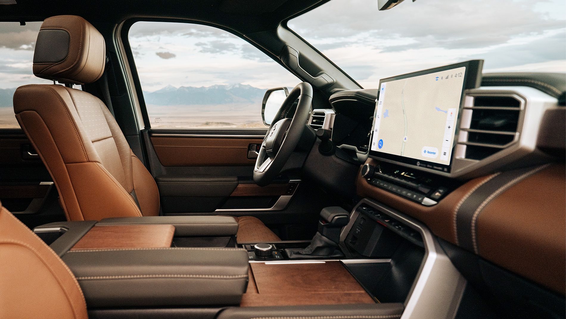 The interior of a toyota sequoia featuring brown leather seats and a large touchscreen display with navigation