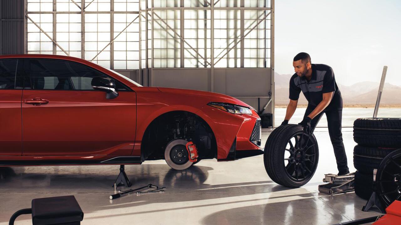 Toyota Service Centers certified technician replaces the tires on a red Toyota sedan
