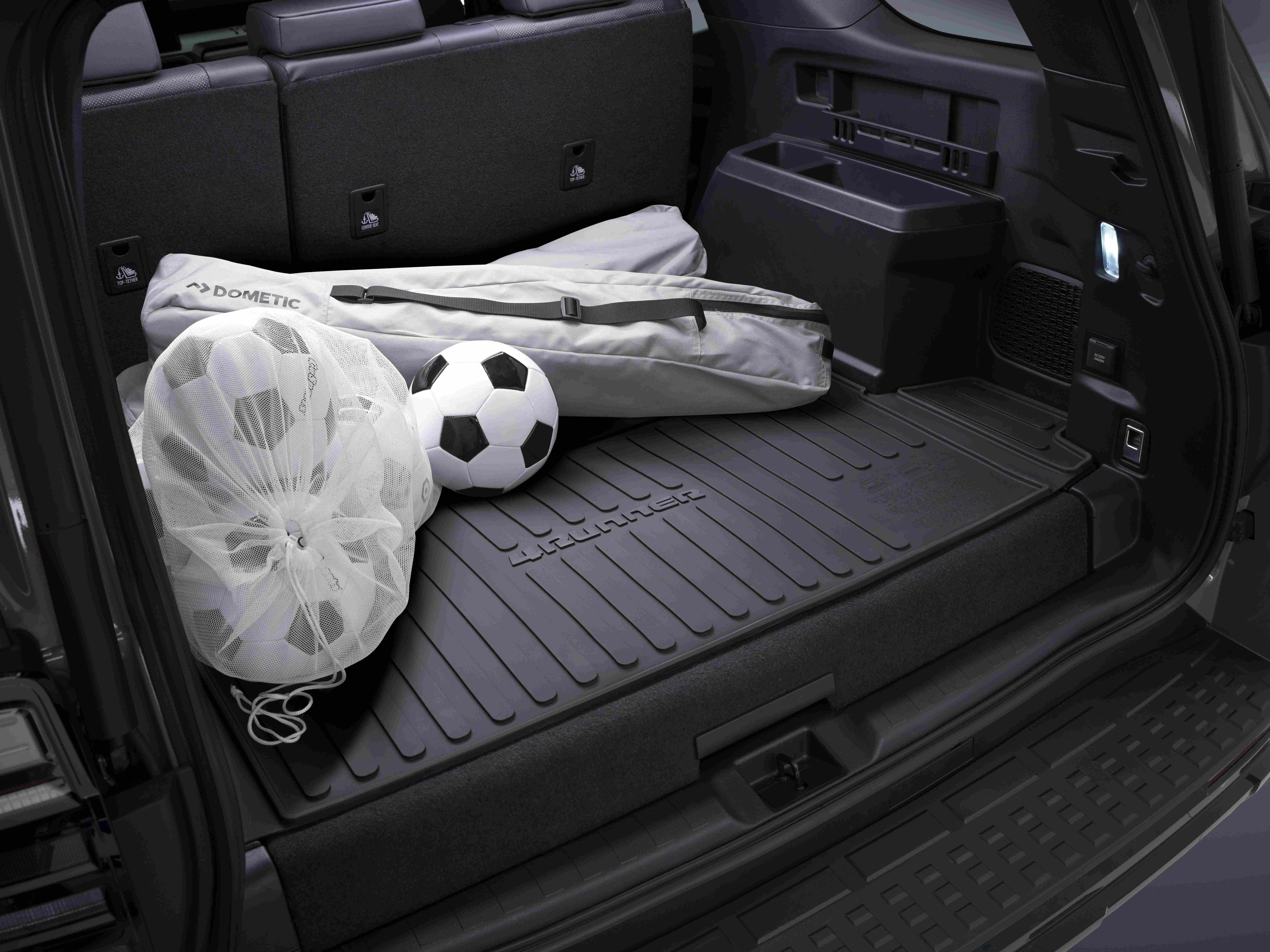 The trunk of an 2025 toyota 4Runner SUV contains a white mesh bag with soccer balls, a single loose soccer ball, and a long gray bag
