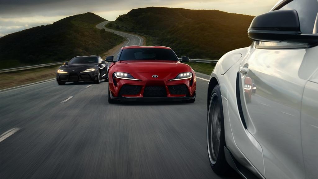 3 Toyota GR Supras racing down a mountain road. red GR Supra, Black GR Supra, White GR Supra