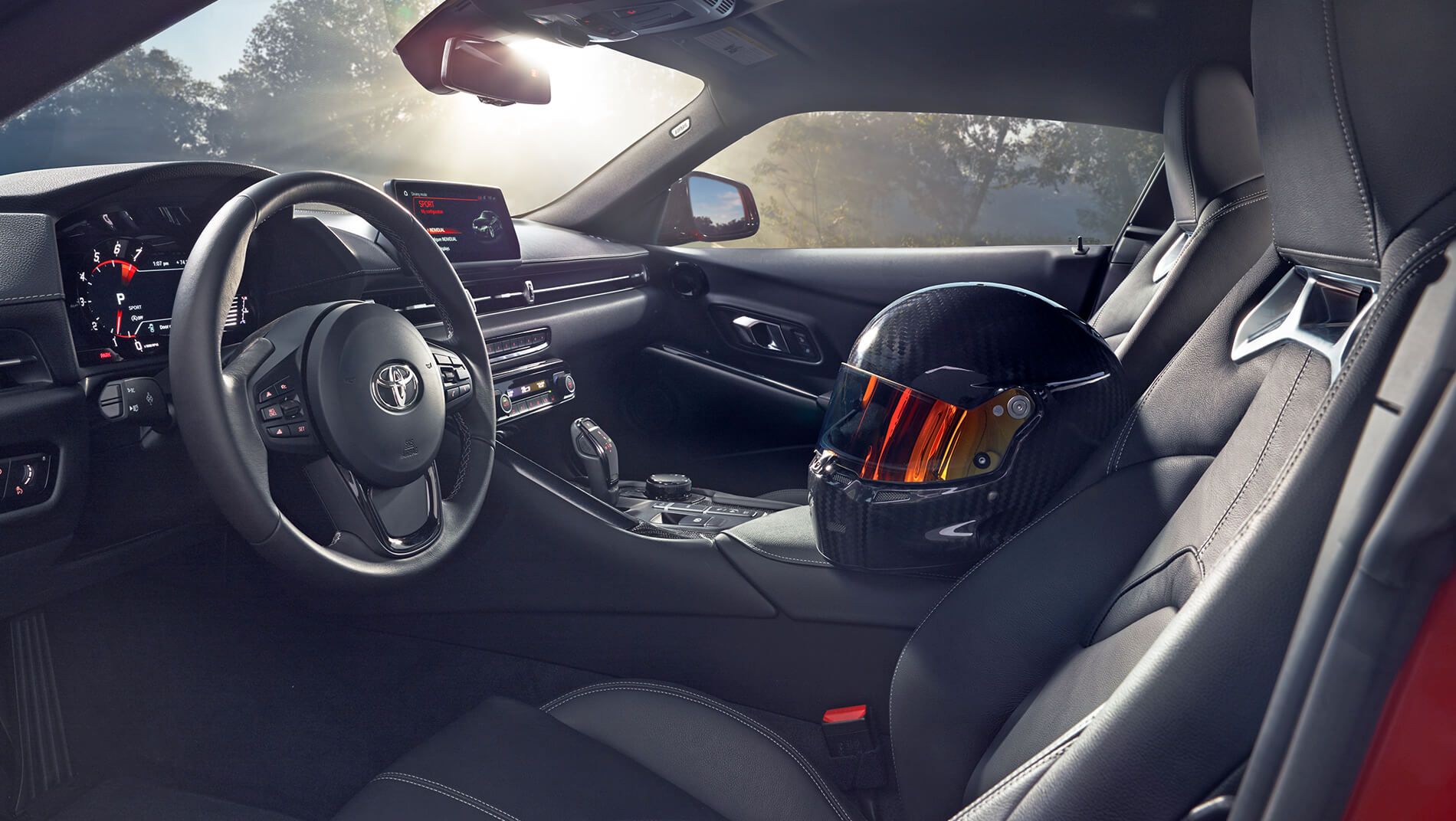 inside of a red Toyota Supra with grey leather interior and a racing helmet inside