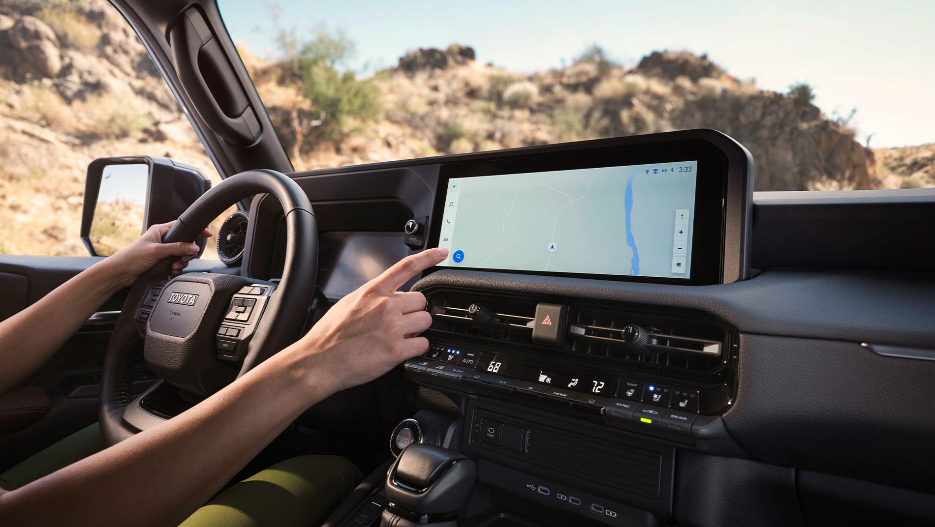 person driving a 2025 Toyota Land Cruiser and using the map on the multimedia navigation touchscreen