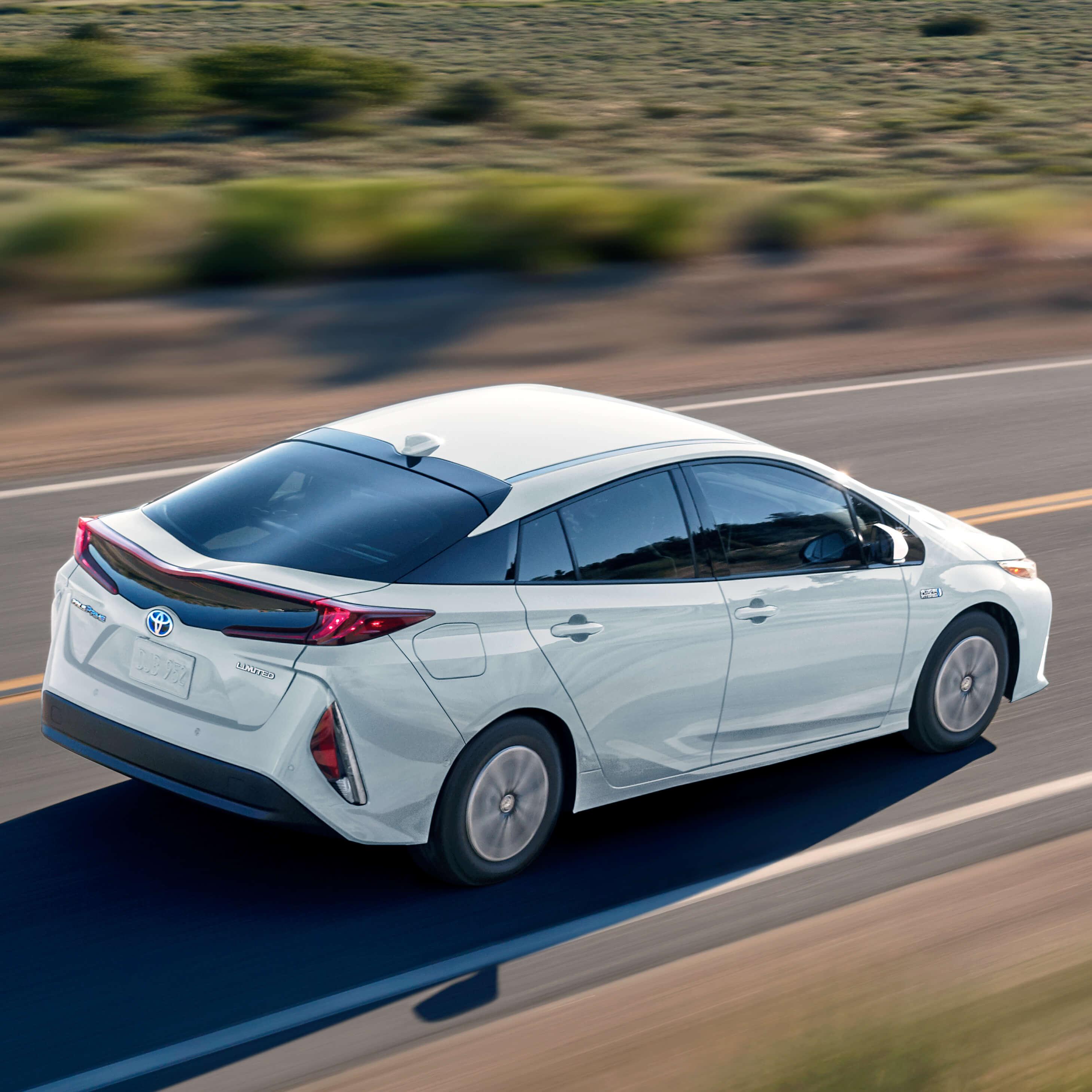 white Toyota Prius Prime plug in hybrid driving down deserted road