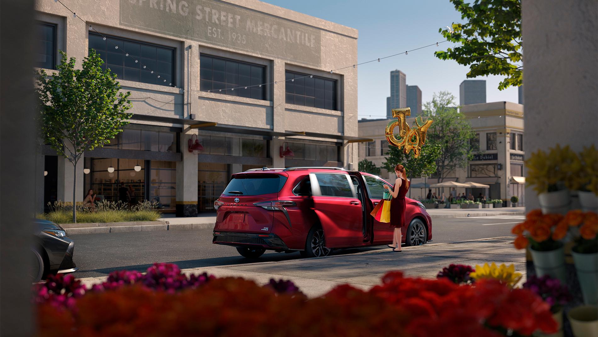 woman putting shopping bags into a red Toyota Sienna hybrid minivan