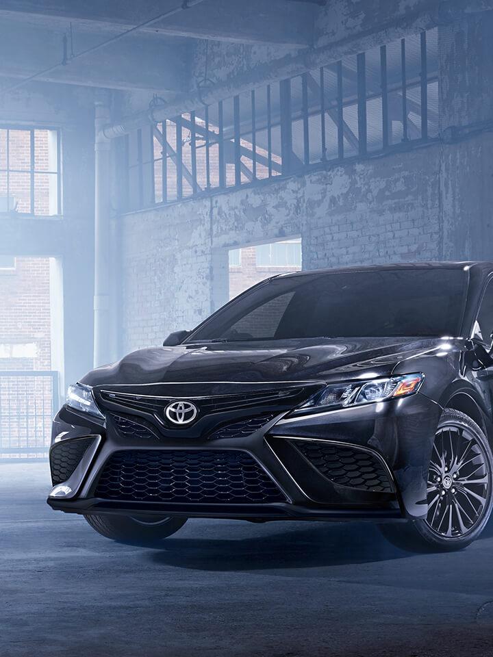 black Toyota Camry in an empty warehouse with light streaming in