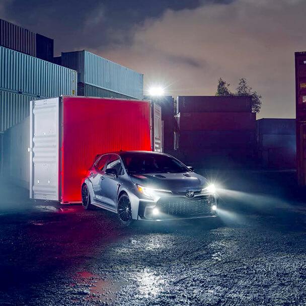 2023 Toyota CR Corolla parked in a shipping yard at night with LED headlights on