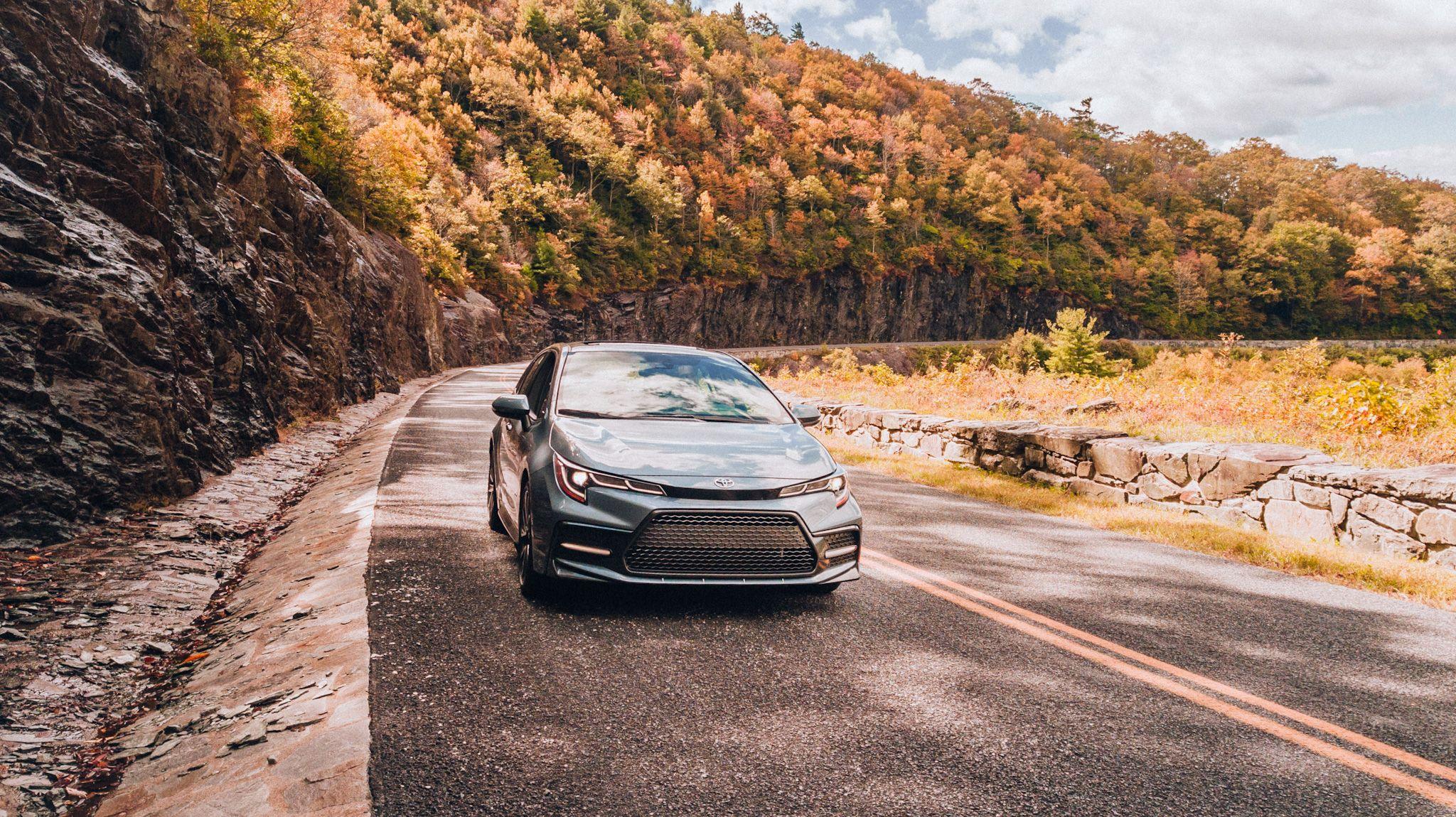 Toyota sedan driving down scenic mountain road