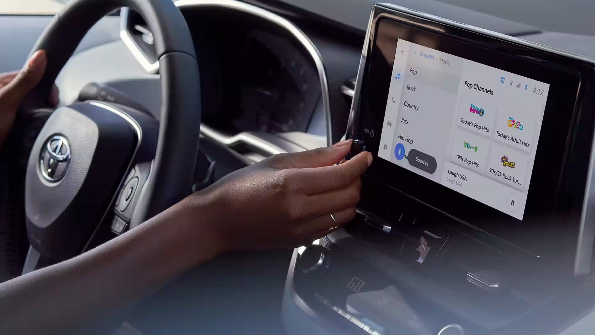 inside a Toyota Corolla hatchback with a woman using the touchscreen control center