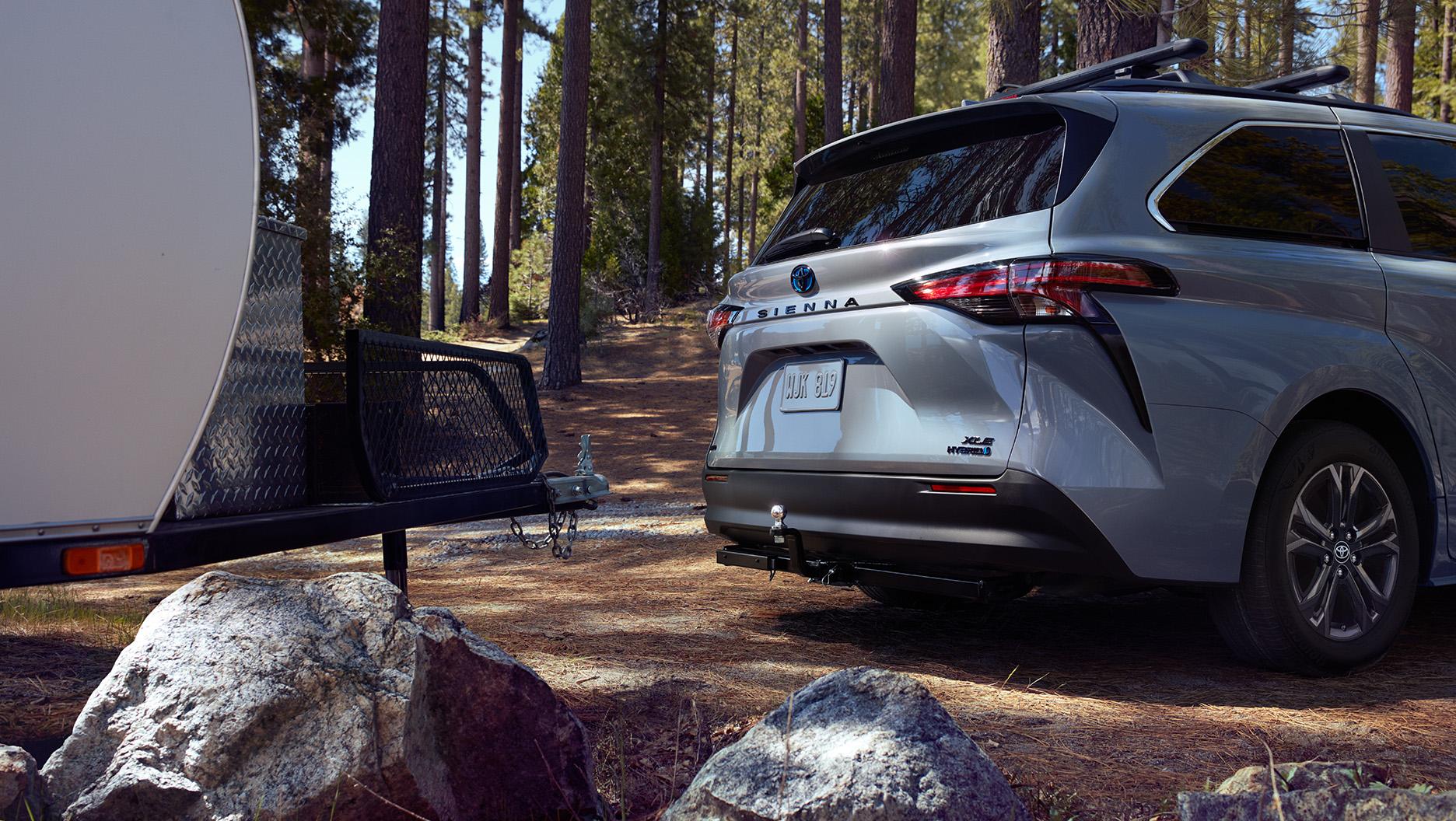 2024 Toyota Sienna sitting in front of a camper having just unhitched at a campsite in the woods