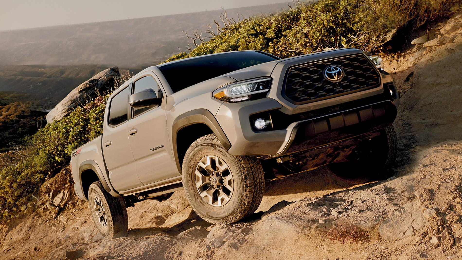 Toyota Tacoma climbing the side of a dusty mountain path