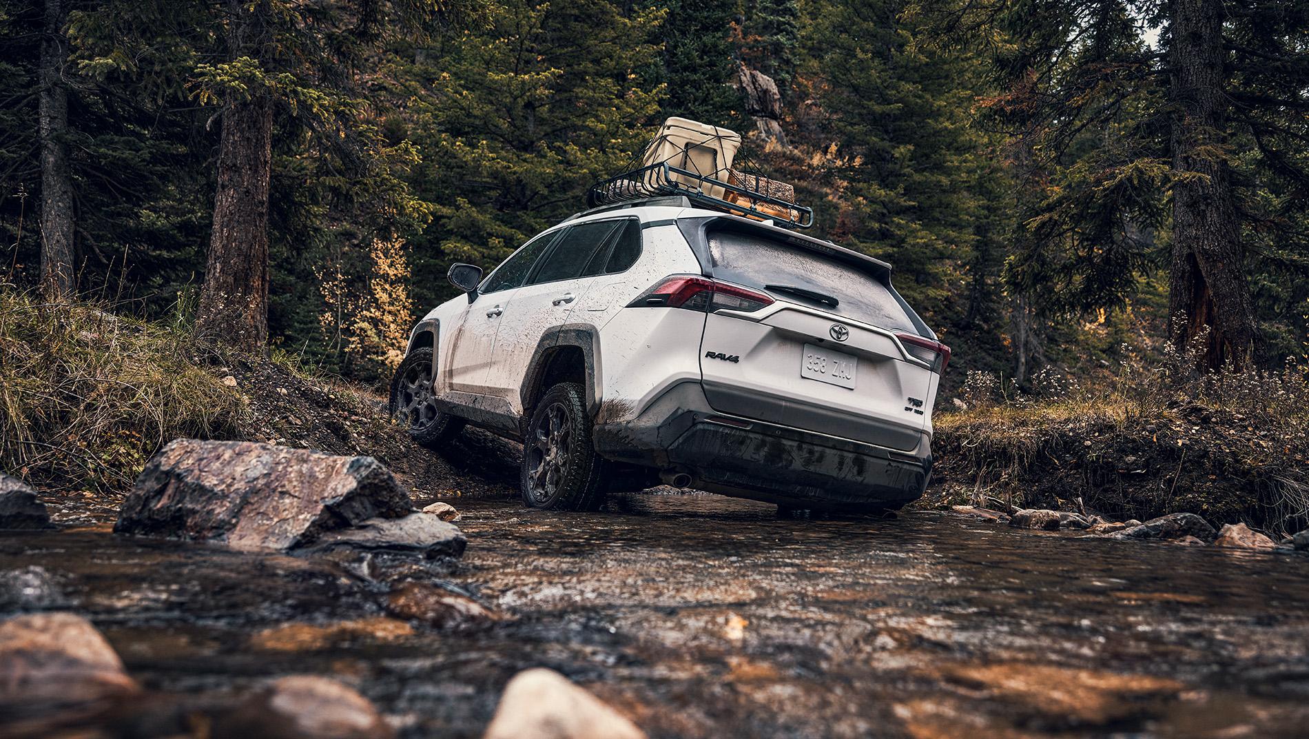 Toyota RAV4 with cargo rack on roof driving through a mountain stream