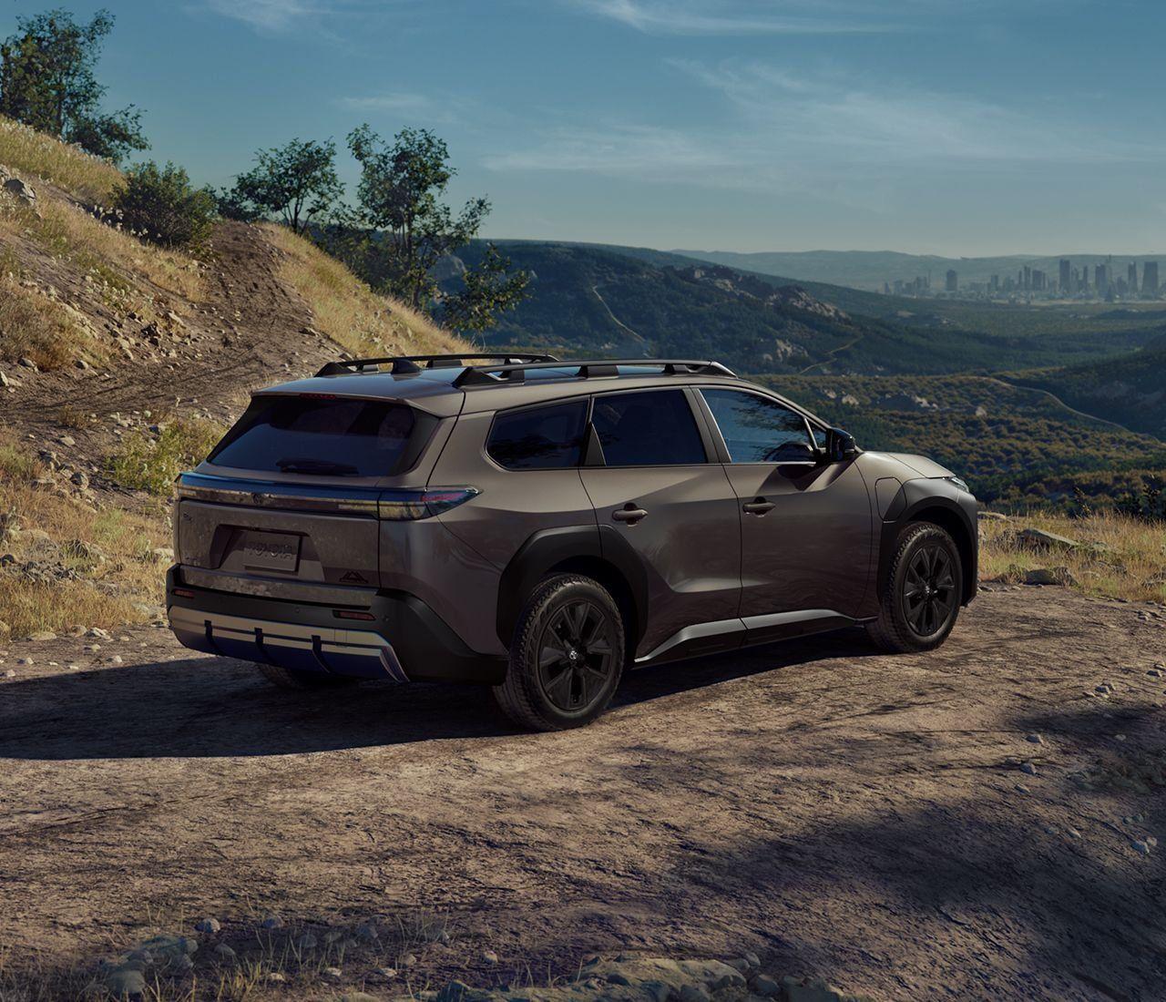 A brown toyota 2026 bzW SUV driving on a dirt road through a hilly landscape.