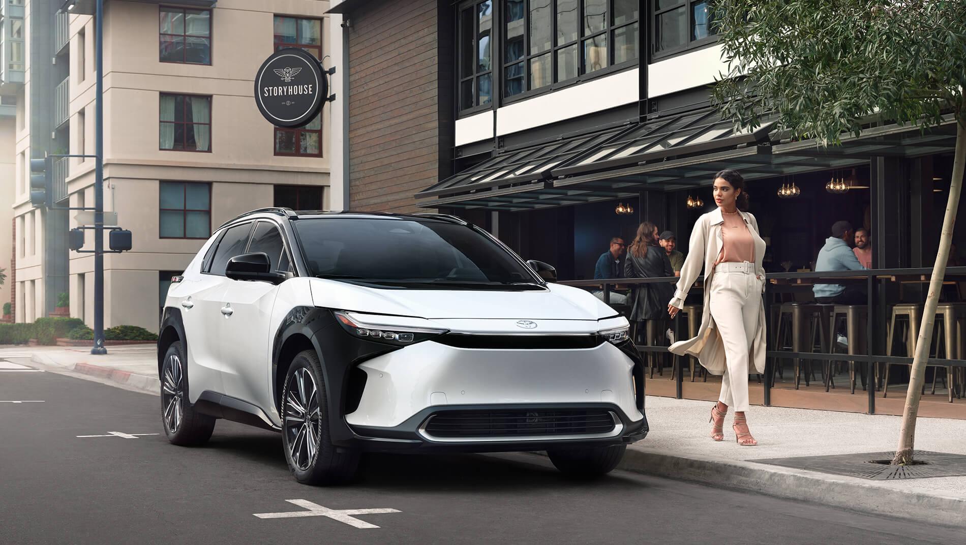 2023 white Toyota bZ4X parked on the street in front of a restaurant in a city