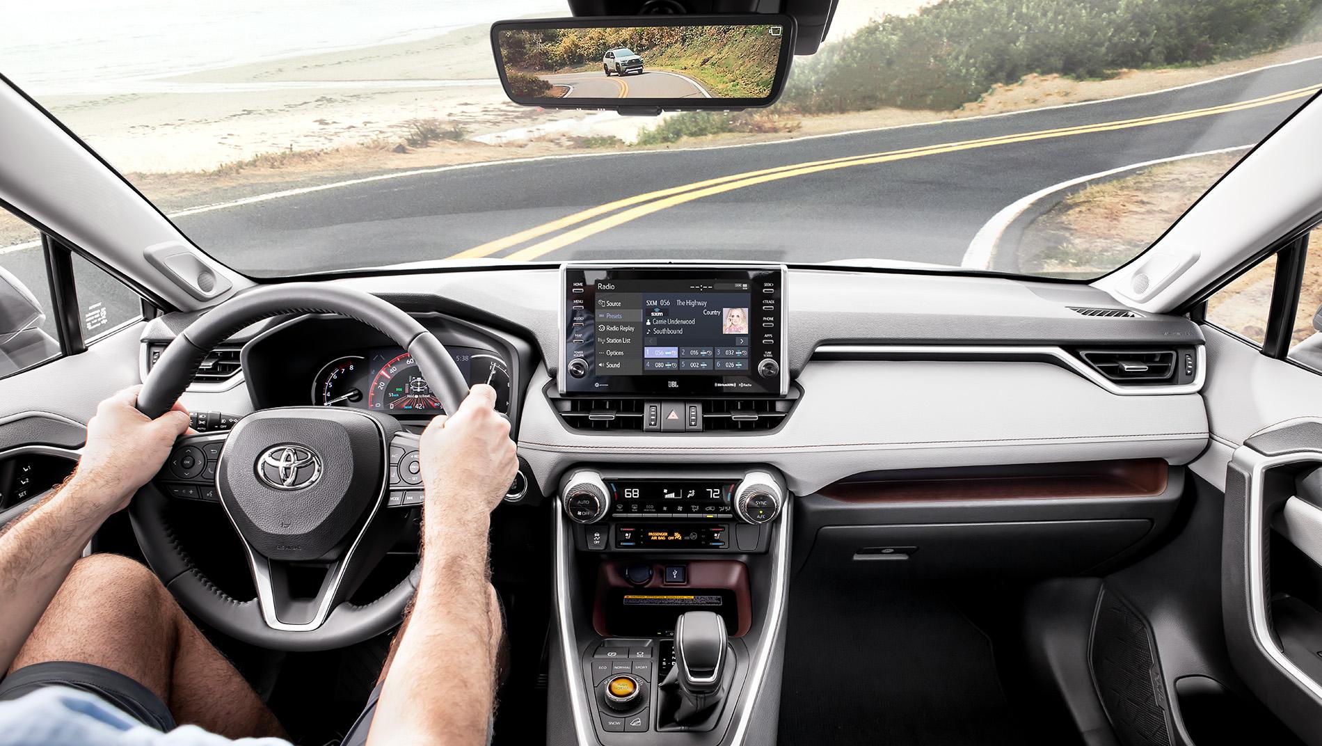 inside a Toyota RAV4 with touchscreen driving on road by the ocean