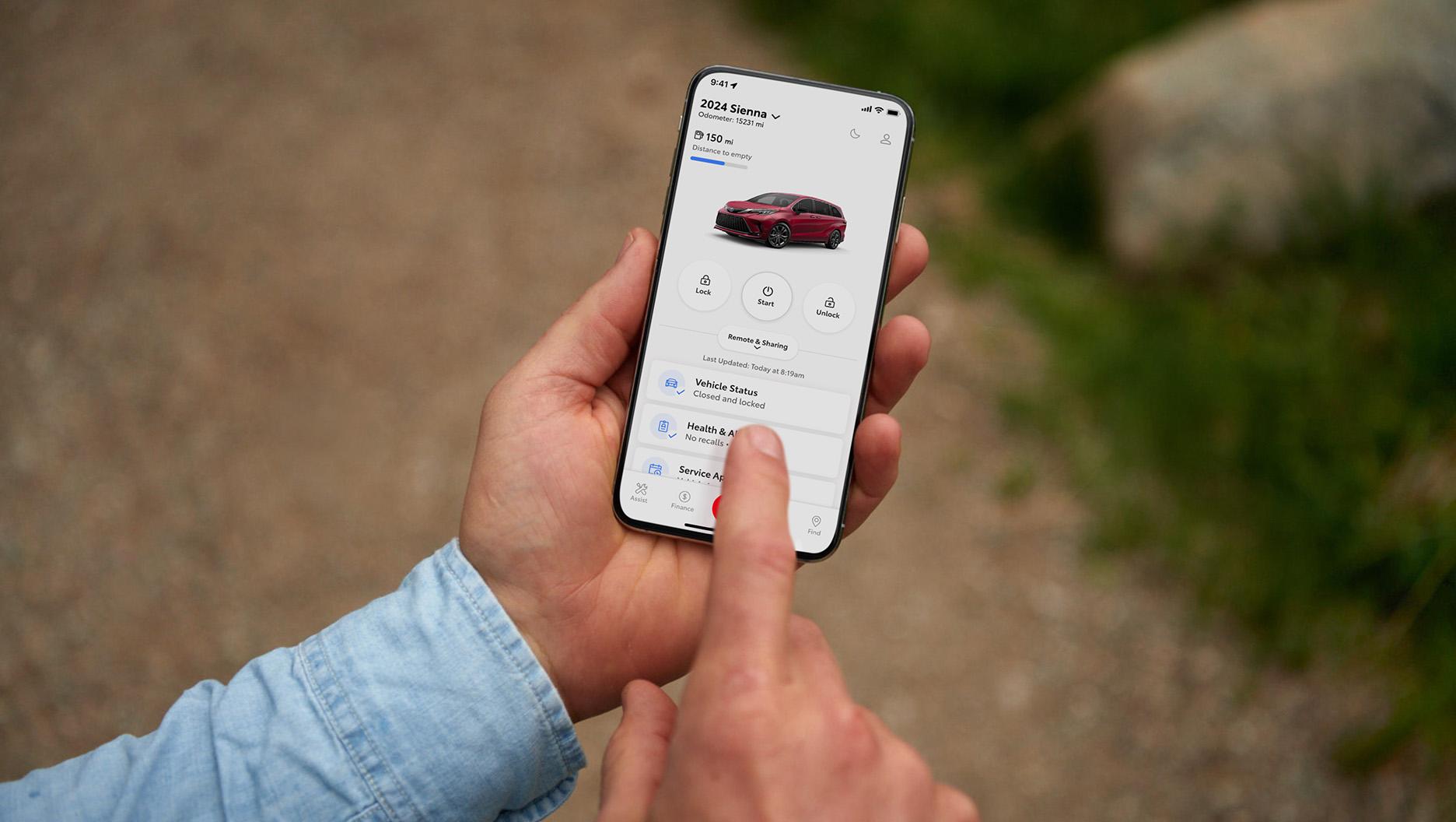 man using the Toyota Connect app on his smart phone to check on the health and maintenance of a Toyota Sienna