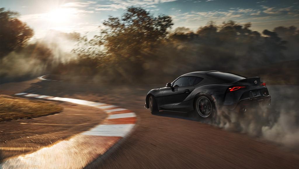 Black Toyota GR Supra going around a left curve on a race track
