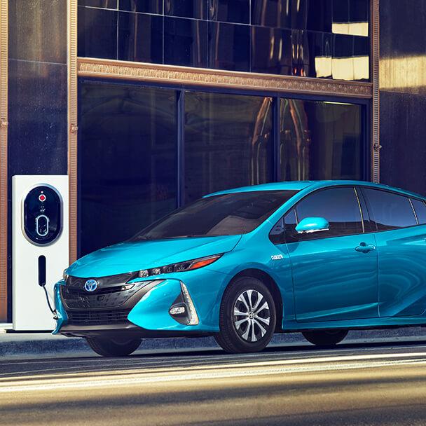blue Toyota Prius Prime charging at a city charging station