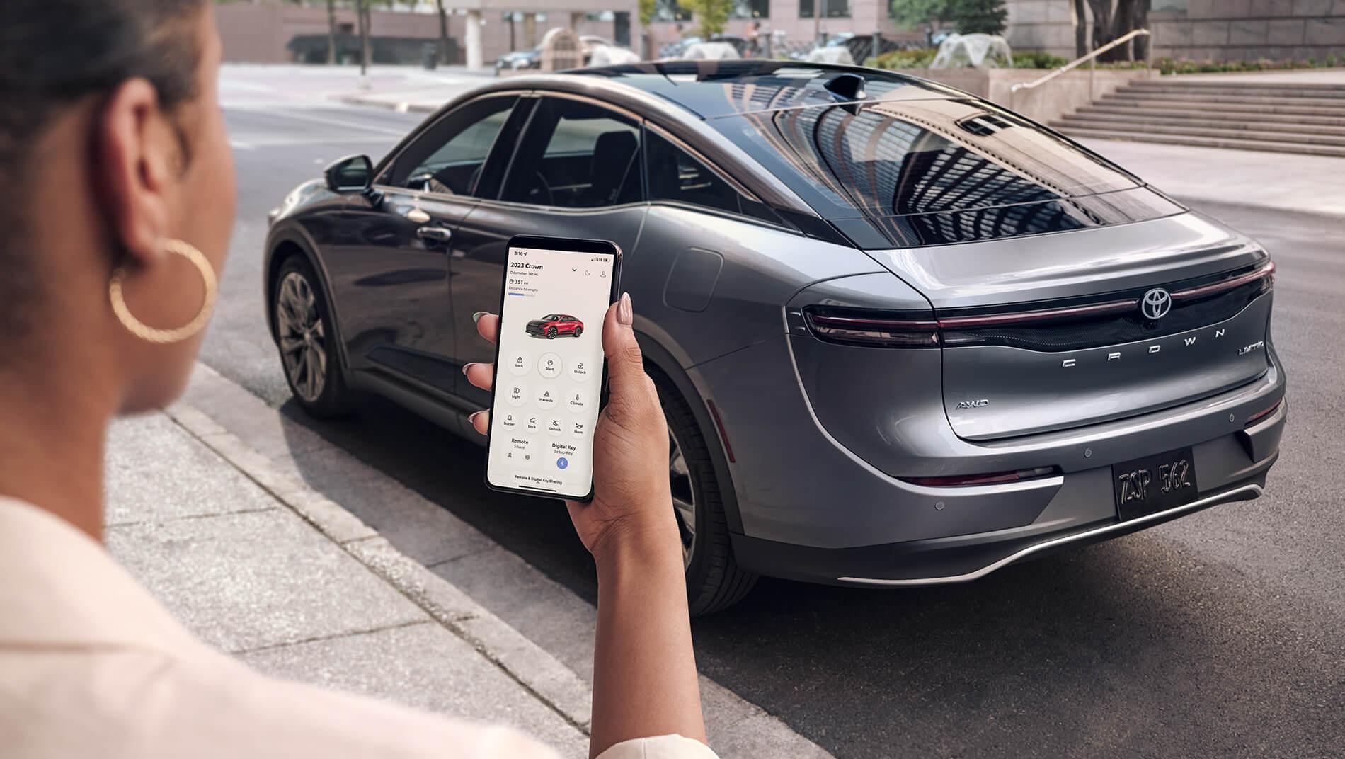 Woman using her Toyota Connected App to control her 2023 Toyota Crown while not inside the car