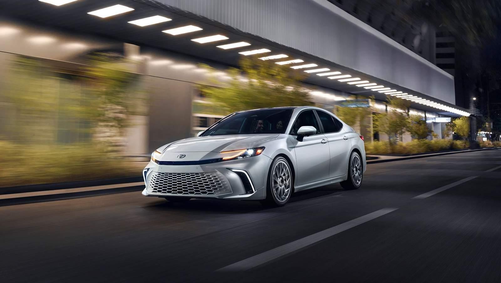 silver 2025 Toyota Camry driving down a city street at night