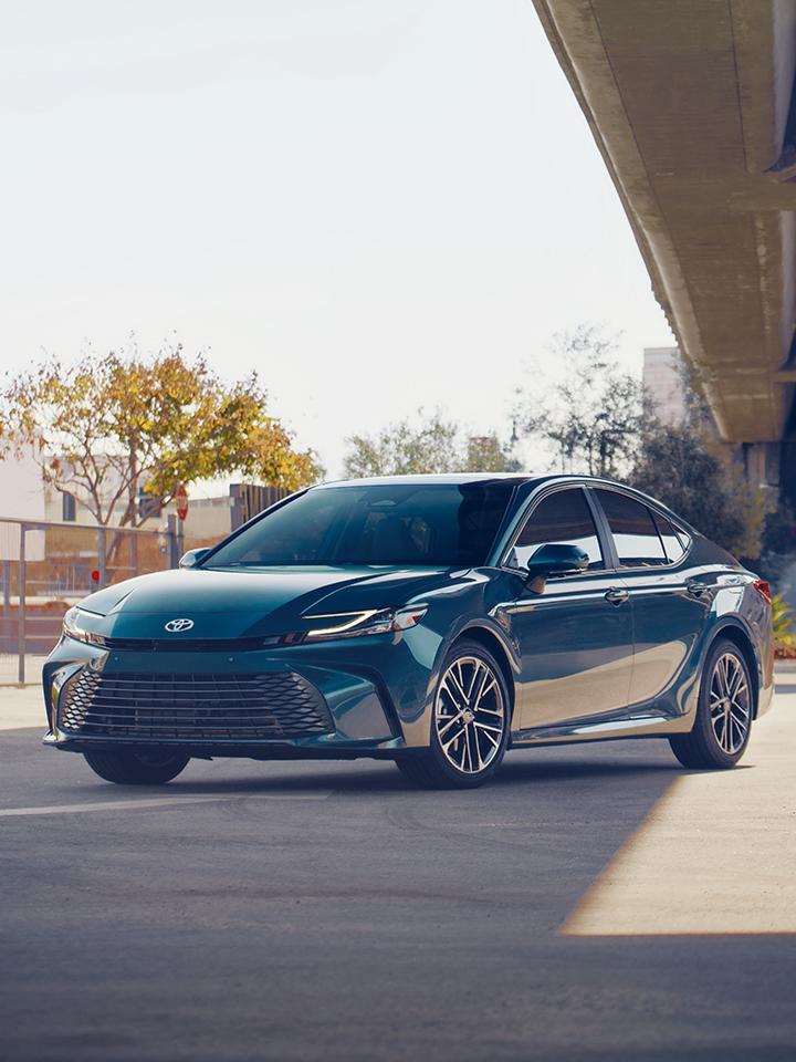 Blue 2025 Toyota Camry parked in a city under a bridge