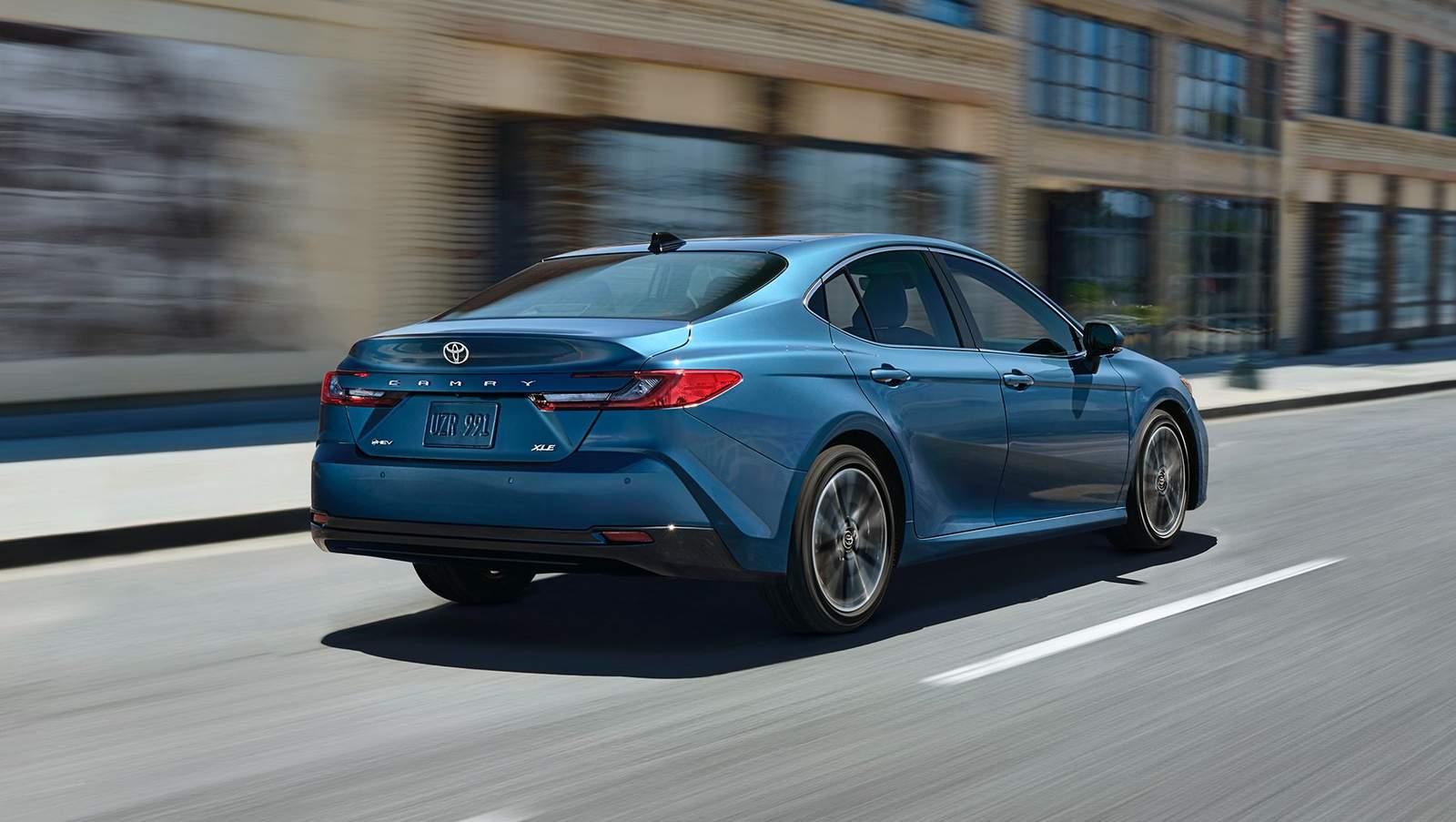 Blue 2025 Toyota Camry drives down an old city street
