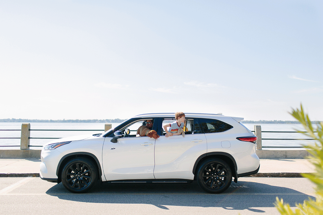 Family inside a White Toyota Highlander XP Xseries parked in front of a large lake