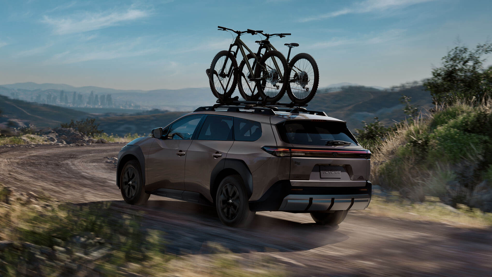 A brown toyota 2026 bzW SUV driving on a dirt road through a hilly landscape.