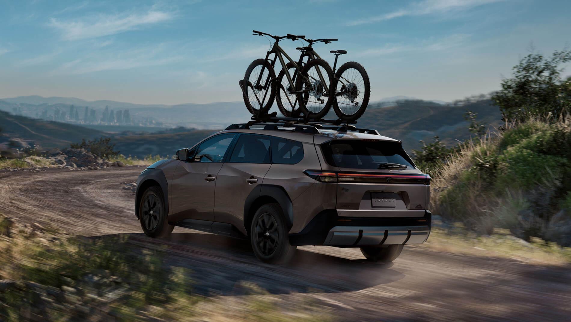 A brown toyota 2026 bzW SUV driving on a dirt road through a hilly landscape.