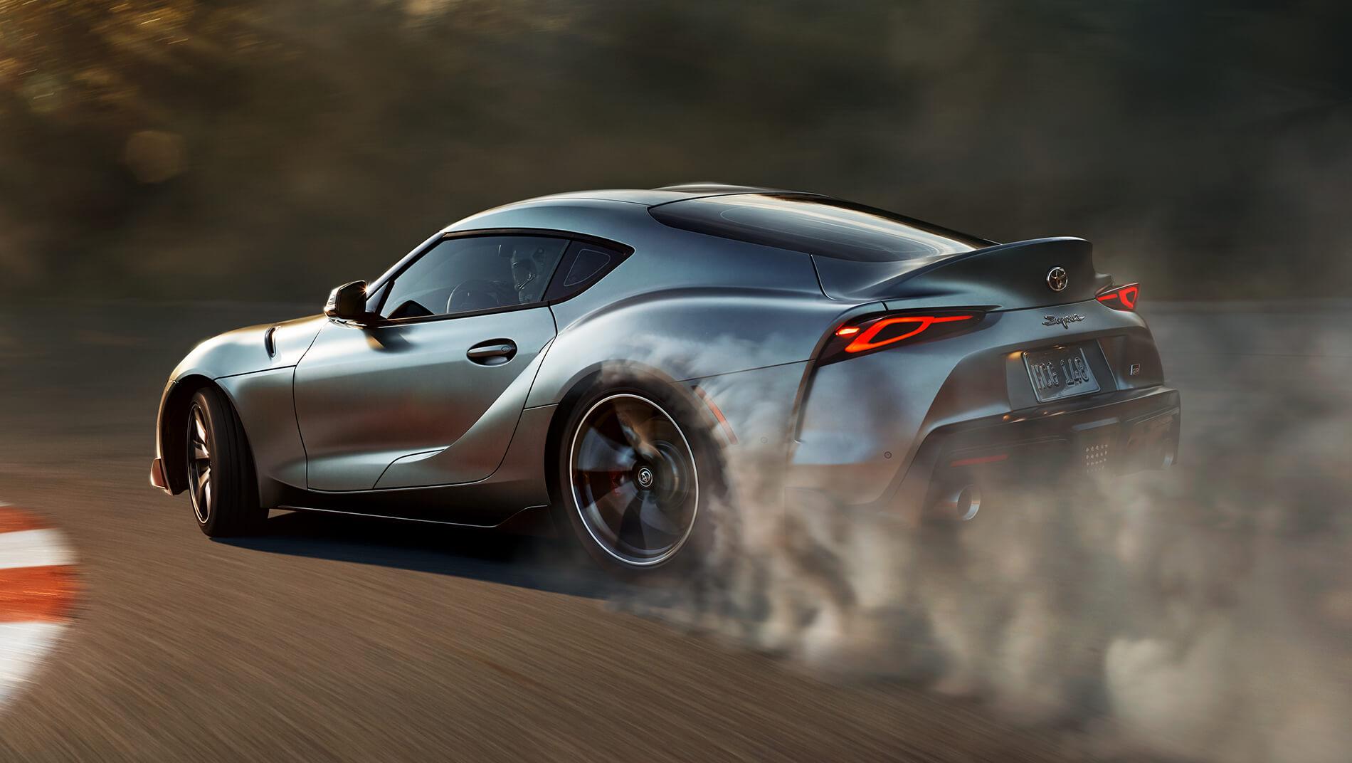 2023 Toyota supra with smoke coming from the tires as it speeds around a race course