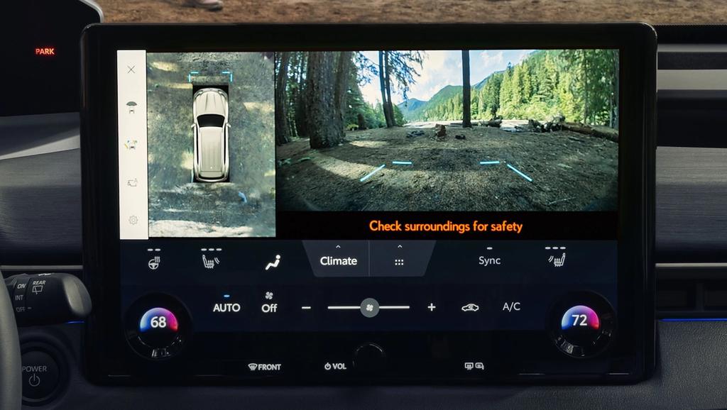 A car dashboard screen displays a 360-degree overhead view and a rear camera view with a forest scene, climate controls, and a safety warning: "Check surroundings for safety.