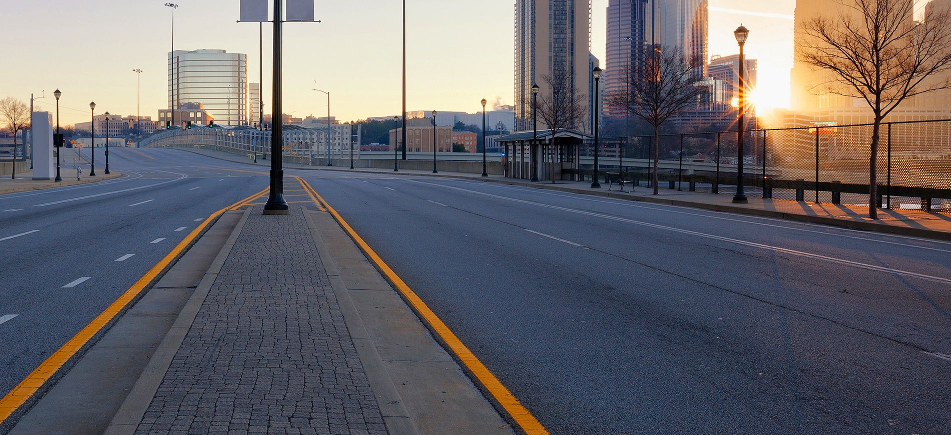 empty road beside city with a few scattered tall buildings