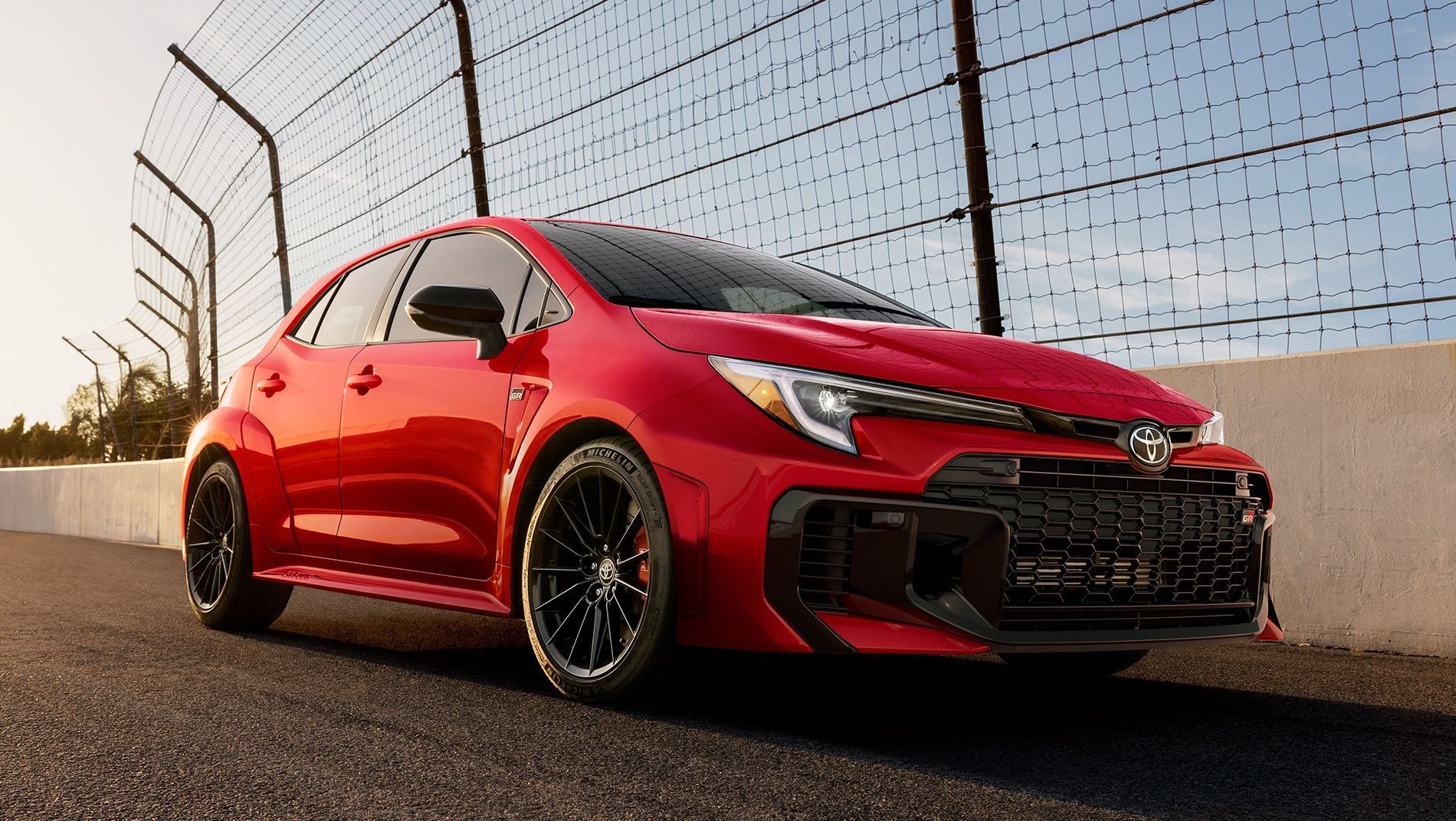 A red Toyota camry sedan with black accents, sporty alloy wheels, and tinted windows