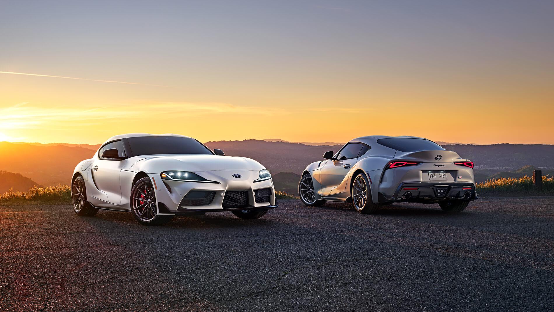 2023 Toyota Supra - 2 vehicles, white and grey = on top of a mountain at sunrise