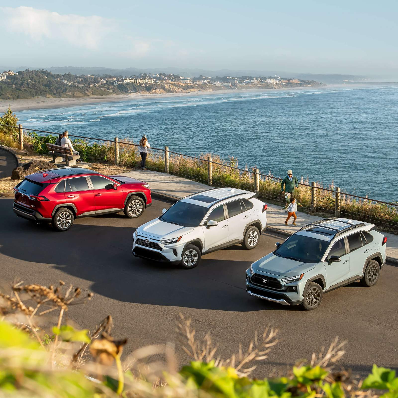 3 Toyota RAV4 SUVs in a parking lot overlooking the ocean with the beach beyond
