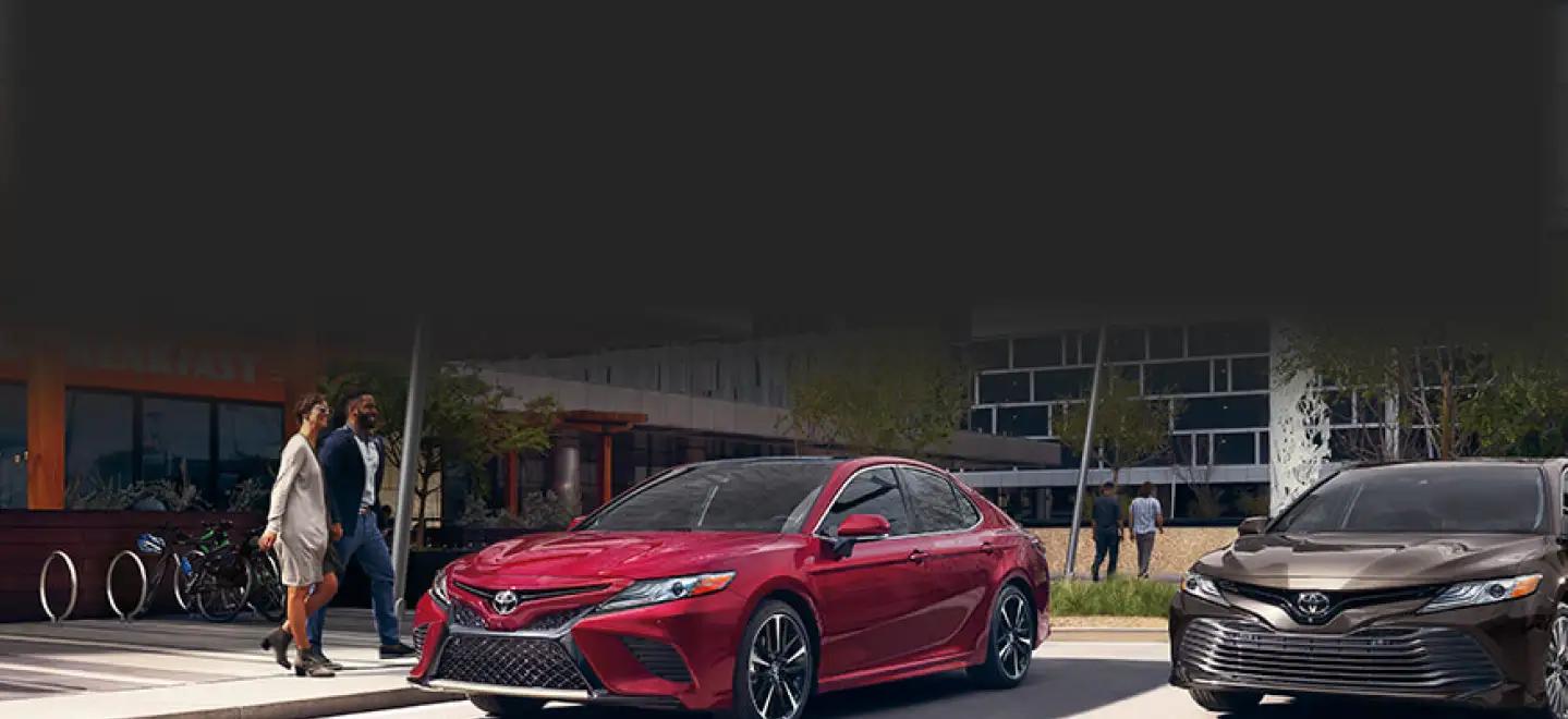 couple walking to a red Toyota sedan from a restaurant in a city