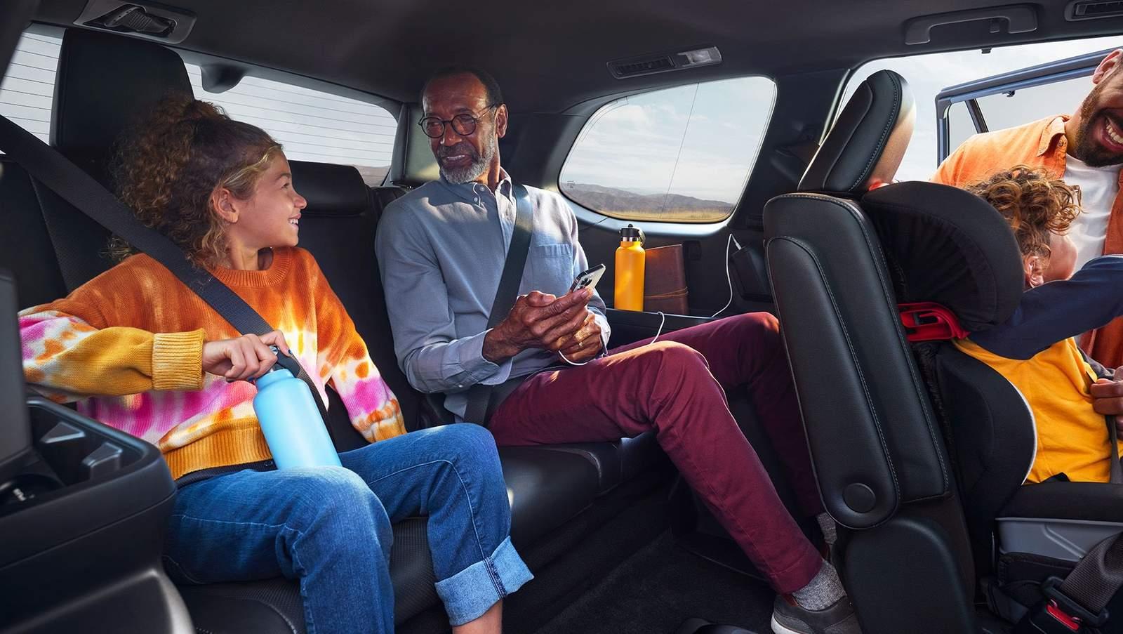 2024 Toyota Grand Highlander inside third row with adult man and teenager and second row with toddler sitting