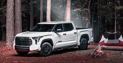 White Toyota Tundra XP XSeries parked at a campsite with a tent and campfire