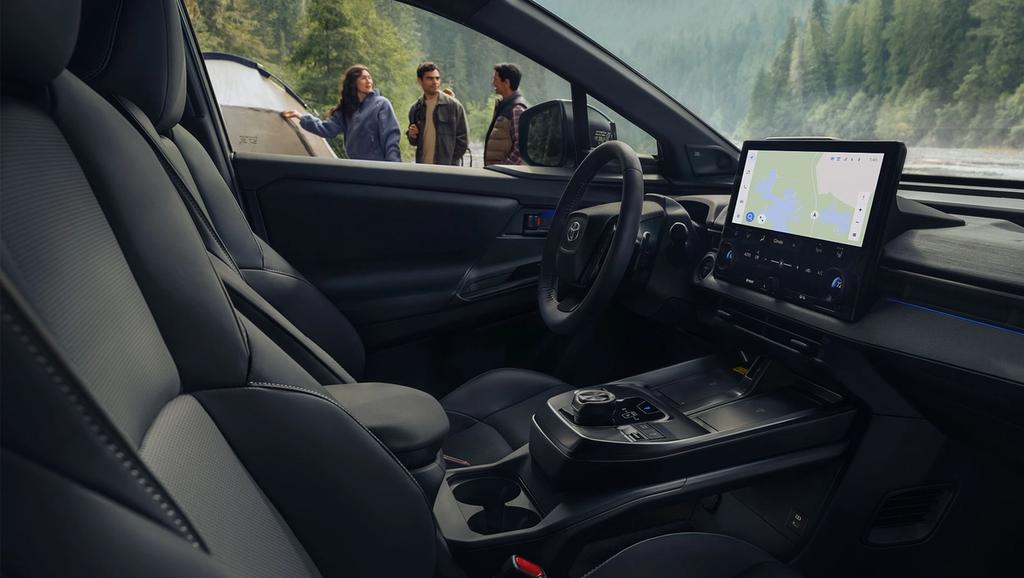 Interior view of a Toyota vehicle featuring the rows of seats in various colors. Is also showing the steering wheel, digital dashboard, and a touchscreen navigation system.