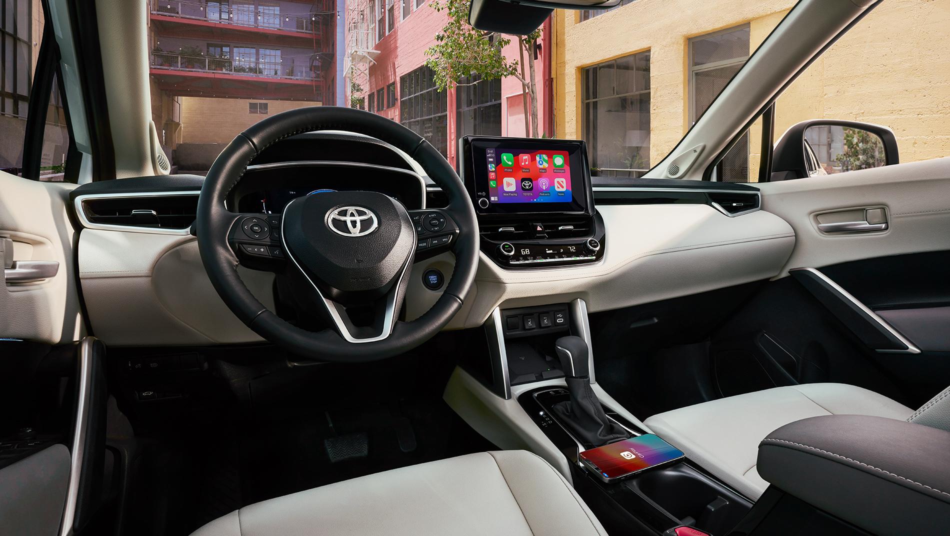 inside a 2024 Corolla Cross Toyota Crossover showing wireless phone charging and the large multimedia touchscreen