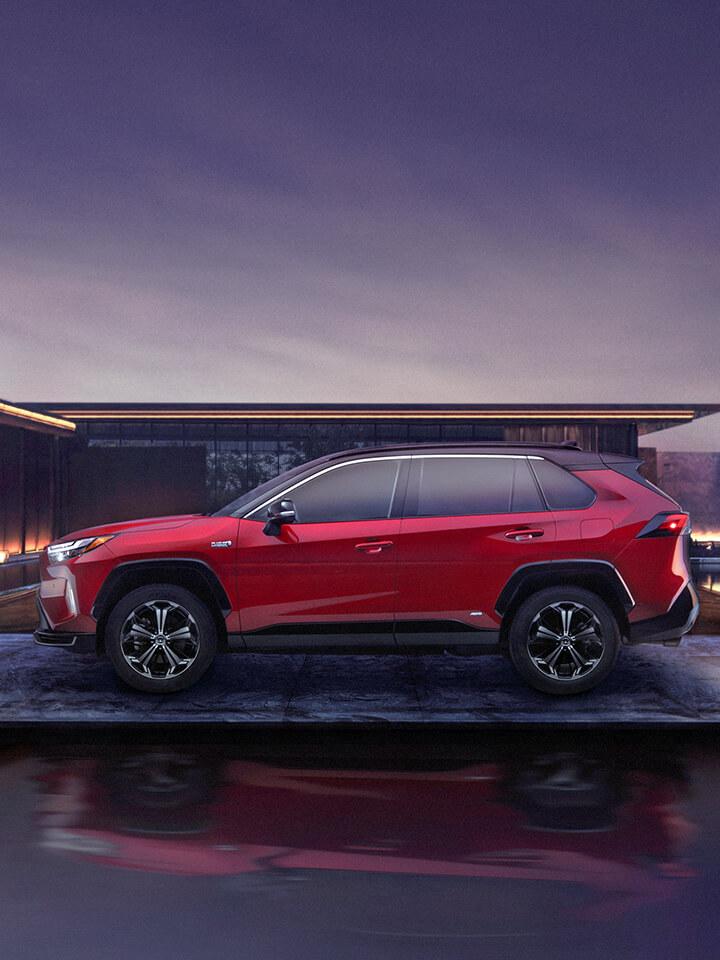 red Toyota RAV4 parked in front of a modern house at night