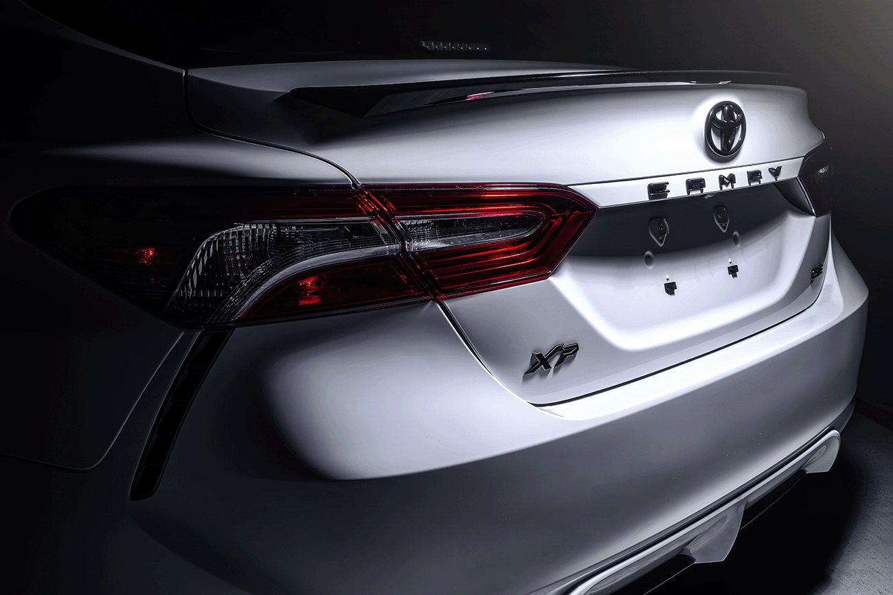 close up of the back and truck of a 2024 white Toyota Camry XP XSeries upgraded accessories package with black emblems and black exhaust tip