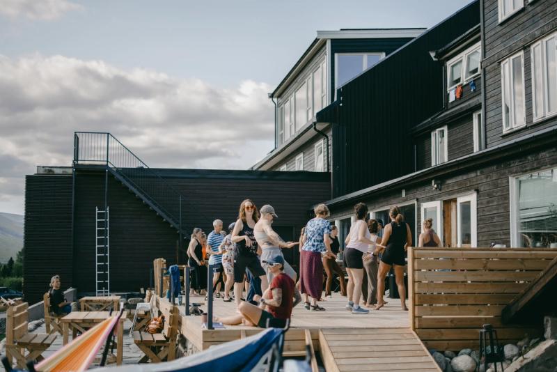 Guests talking on the sunlit deck outside the hotel