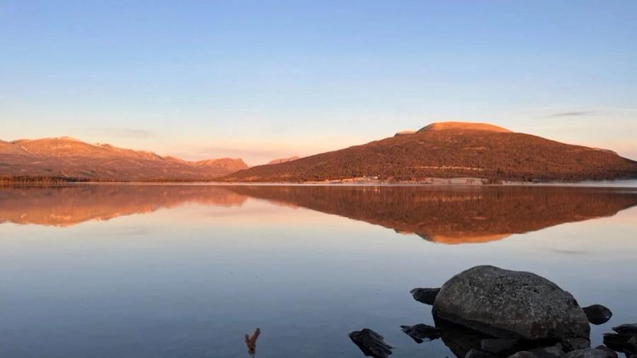 Et blikkstille fjellvann i solnedgang