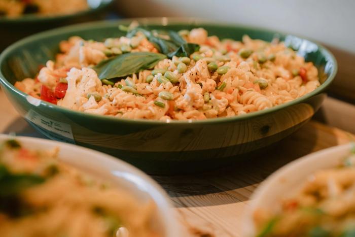En grønn bolle med pastasalat med blomkål, erter og basilikum på buffeten