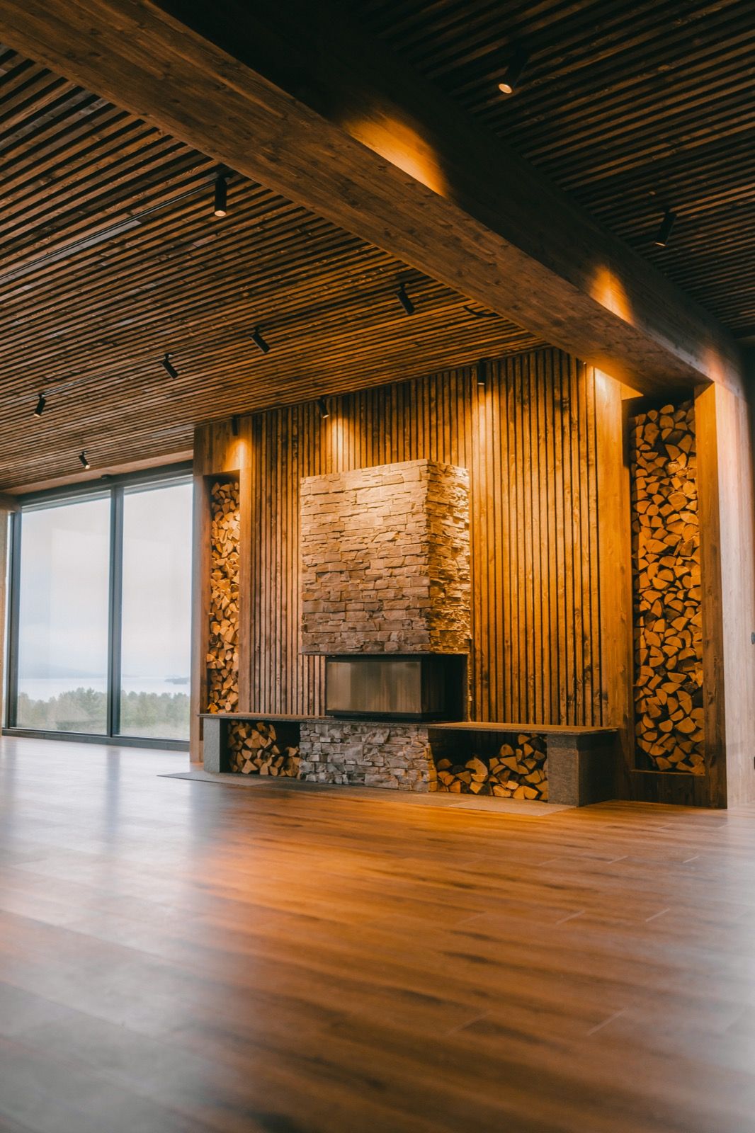 Shala Lakshmi: a tall wooden hall with a slatted ceiling and a stone fireplace