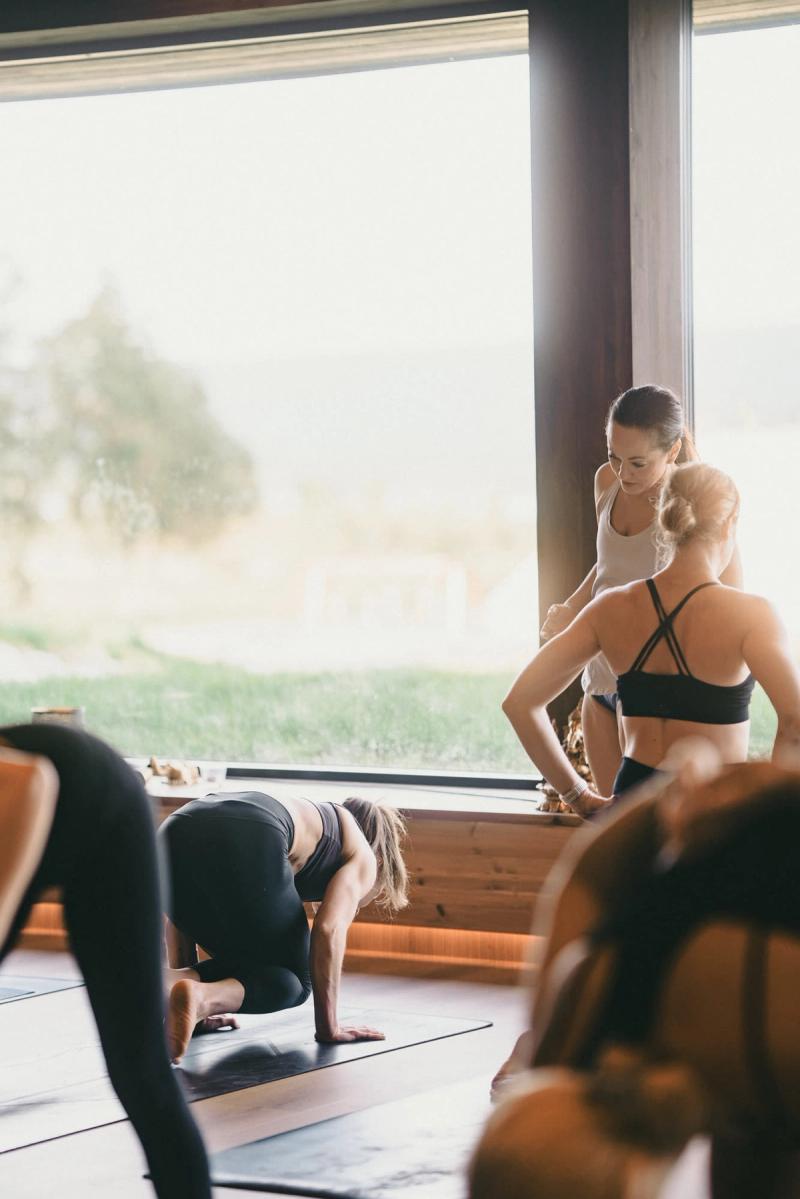 A yoga class in the shala, the teacher watching from the window