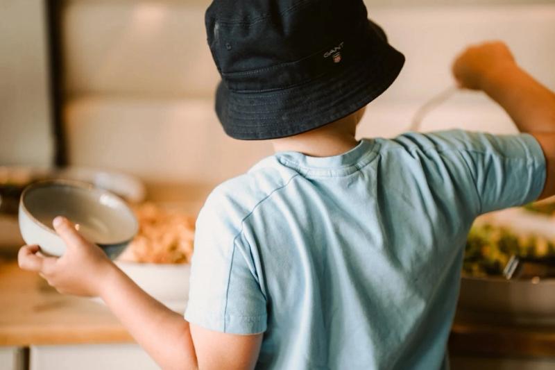 A child in a sun hat reaching for food at the buffet